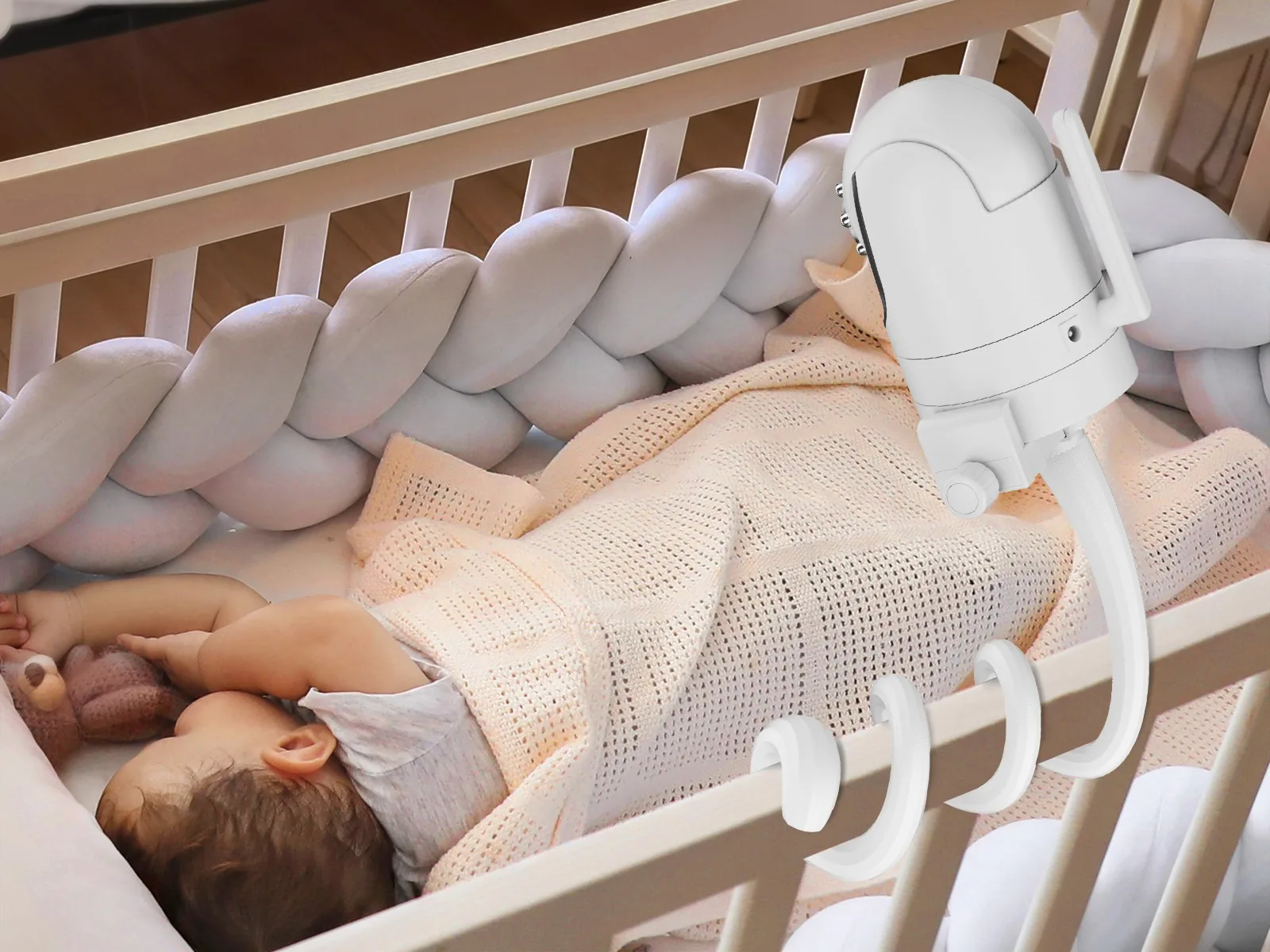 White gooseneck baby monitor mount wrapped around a crib rail above a sleeping baby