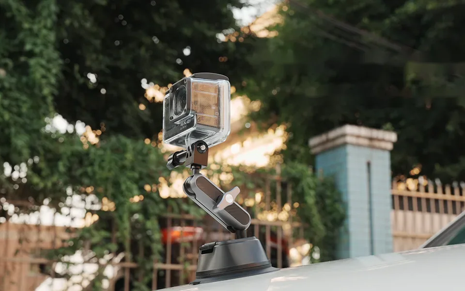Action camera on a suction-cup mount with a metal arm on a car roof